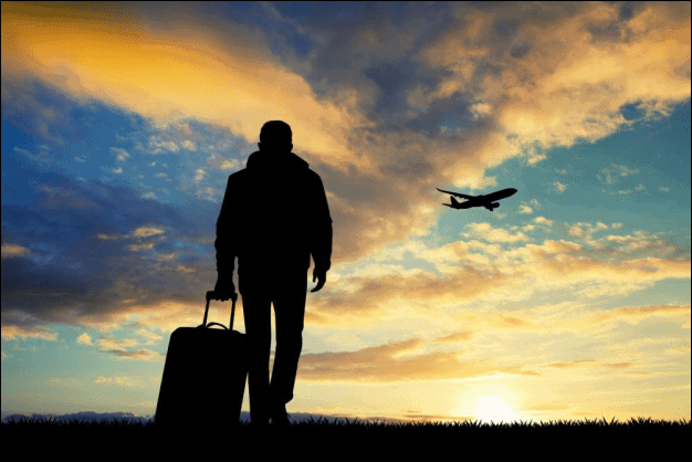 Silhouette of a Man Walking with a Travel Suitcase.