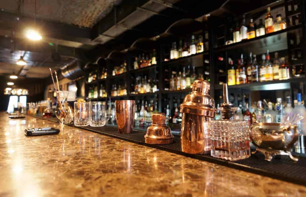  Un regard attentif sur un comptoir de bar avec un fond de liqueurs sur des étagères.