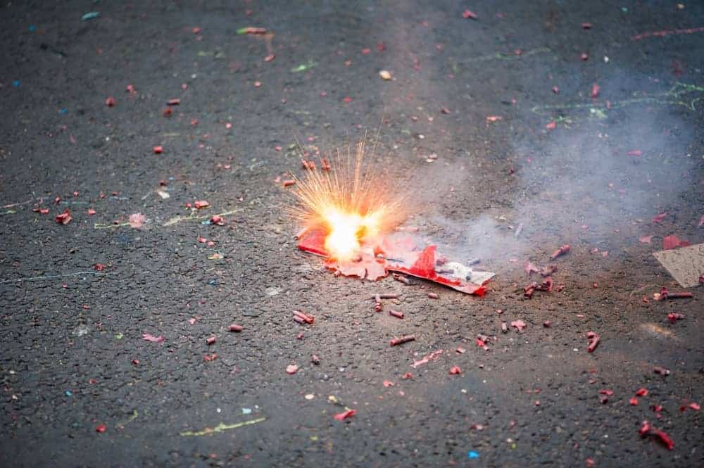 A close look at firecrackers exploding on the asphalt ground.