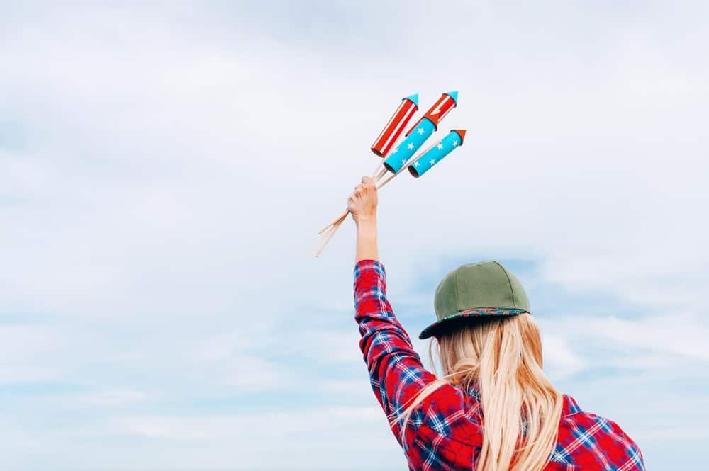 A woman holding four unlit missile fireworks up in the air.