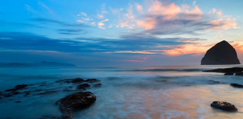 Oregon coastline with clouds and off shore rocks at sunset.