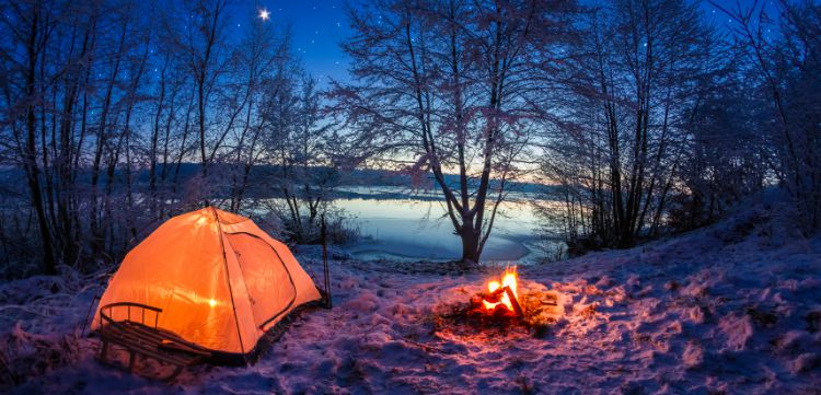 Camping by a lake with a tent and camp fire.