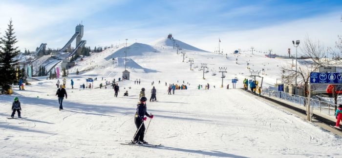 Skiers with kids on a local mountain park enjoying a sunny day skiing.